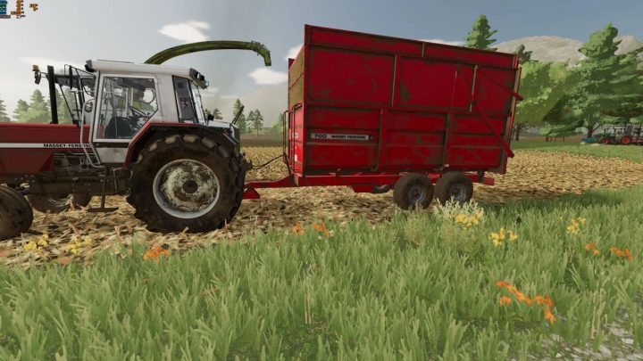 FS22 Massey Ferguson 700 mod toont een rode tractor met aanhanger in een grasveld. Farming Simulator 22 mods verbeteren de gameplay.