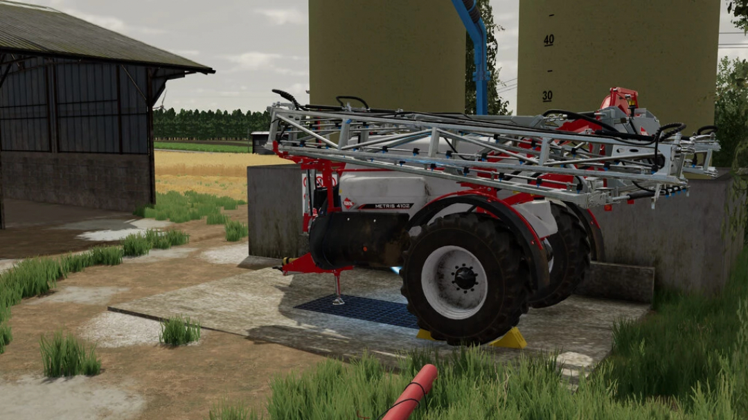 Sprayer KUHN METRIS 4102 v1.0.0.0 mod for FS22 near a barn and field.