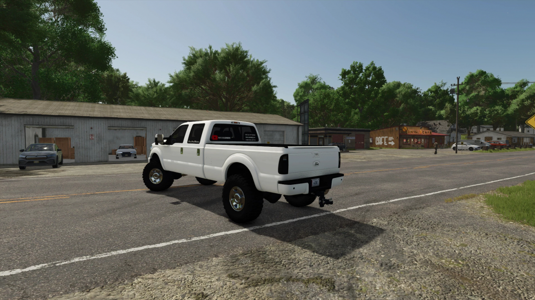 2016 Ford F350 mod in FS25 driving through a rural town with trees and cafes in Farming Simulator 25.