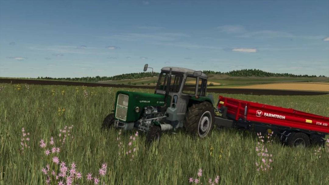 FS25 URSUS C355 ZIELONA mod tractor in a field towing a red trailer in Farming Simulator 25.