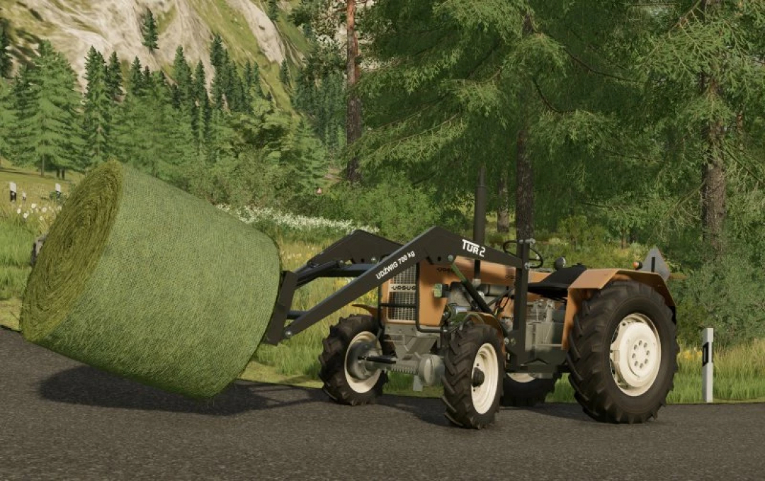 FS22 mod Ursus C330 tractor carrying a hay bale in a lush forest setting.