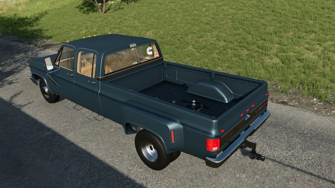 Chevrolet K30 Dually mod in FS22, version 1.2.0.0. Features a dark blue pickup with dual rear wheels, parked on a road with grassy surroundings.