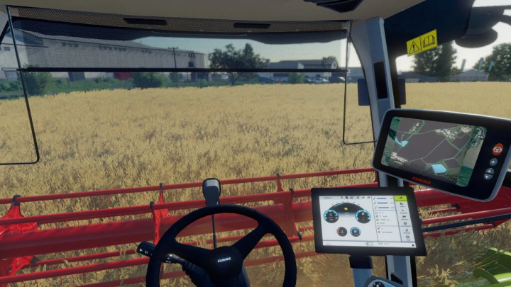 fs22-mods,  View from inside Claas Tucano 550-580 in FS22 mod, showing control screens overlooking a wheat field.