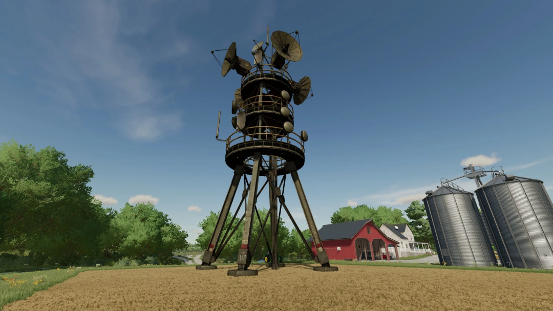 Mod FS22 Military Antenna com uma grande torre de antenas em terras agrícolas com silos e edifícios ao fundo.