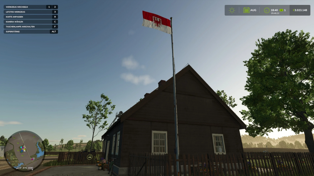 FS25-Mod zeigt die Flagge von Brandenburg neben einem rustikalen Haus unter klarem Himmel.