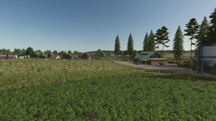 fs25-mods,  Scenic view of Zielonka Forestry Edition in FS25, featuring lush fields, trees, and farm buildings under a clear blue sky.