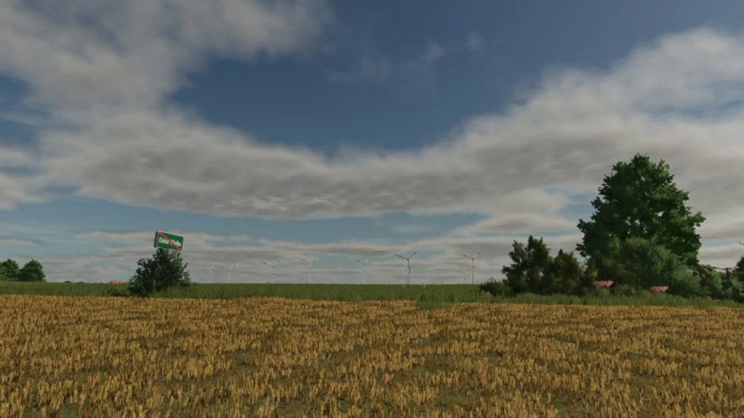 Scenic view in FS25 Osina Wielka mod showing a vast field, wind turbines, and trees under a partly cloudy sky.