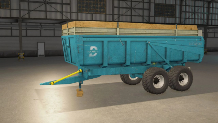 fs25-mods,  Duchesne 14T trailer in FS25 mod showcasing a blue agricultural trailer with dual axles, inside a warehouse.