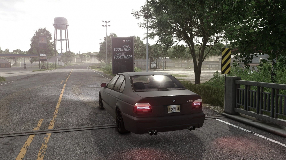 BMW E39 mod in Farming Simulator 25, driving on rural road, surrounded by trees, signboard visible.