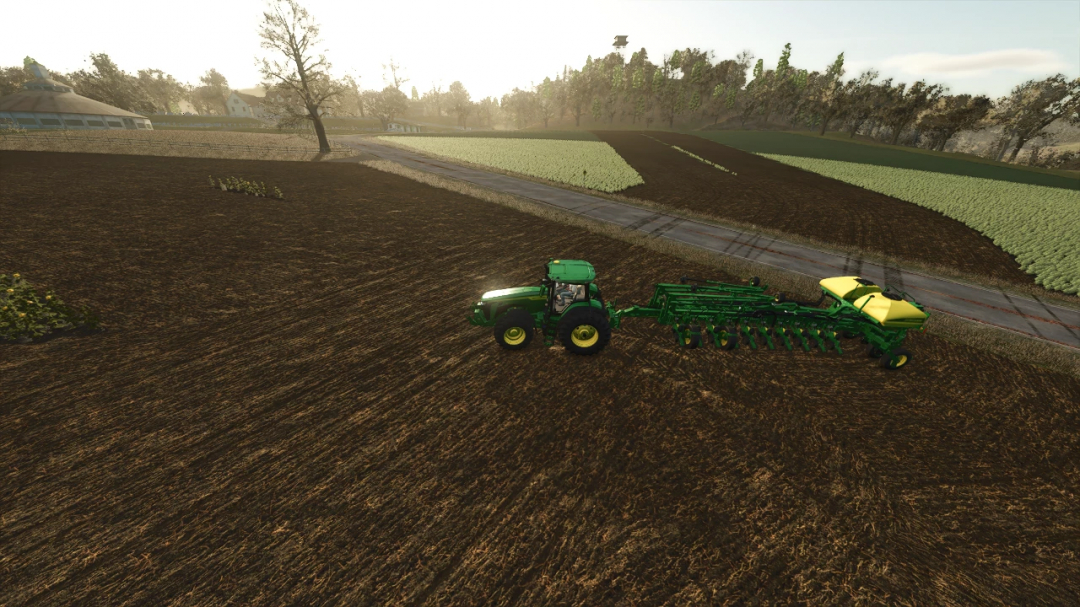 John Deere planter in FS25 mod on a plowed field with trees and farm buildings in background.