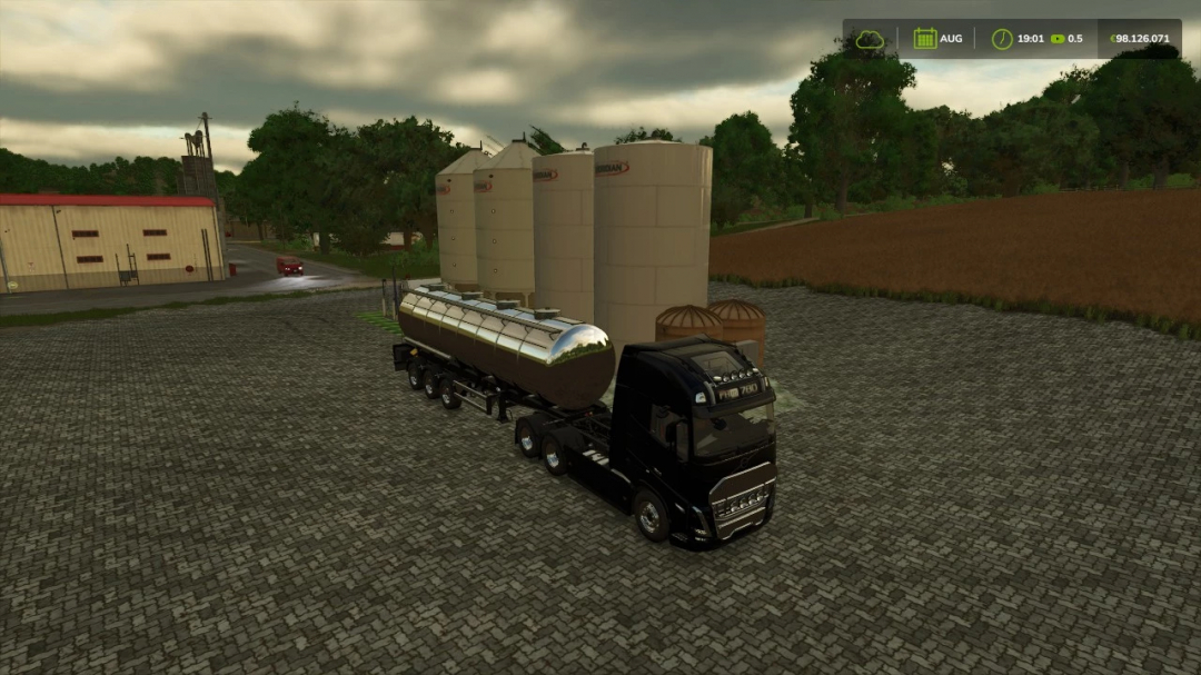 FS25 mod showing a black truck with a tanker trailer near grain silos in Farming Simulator 25.