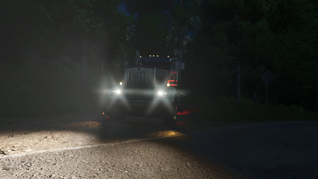 FS25 Kenworth W900L mod showcasing truck headlights illuminating a dark forest path.