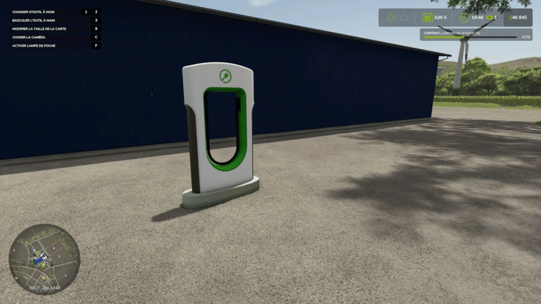 FS25 mod Super Charger Station v1.0.0.0 in Farming Simulator 25, located by a large blue building.