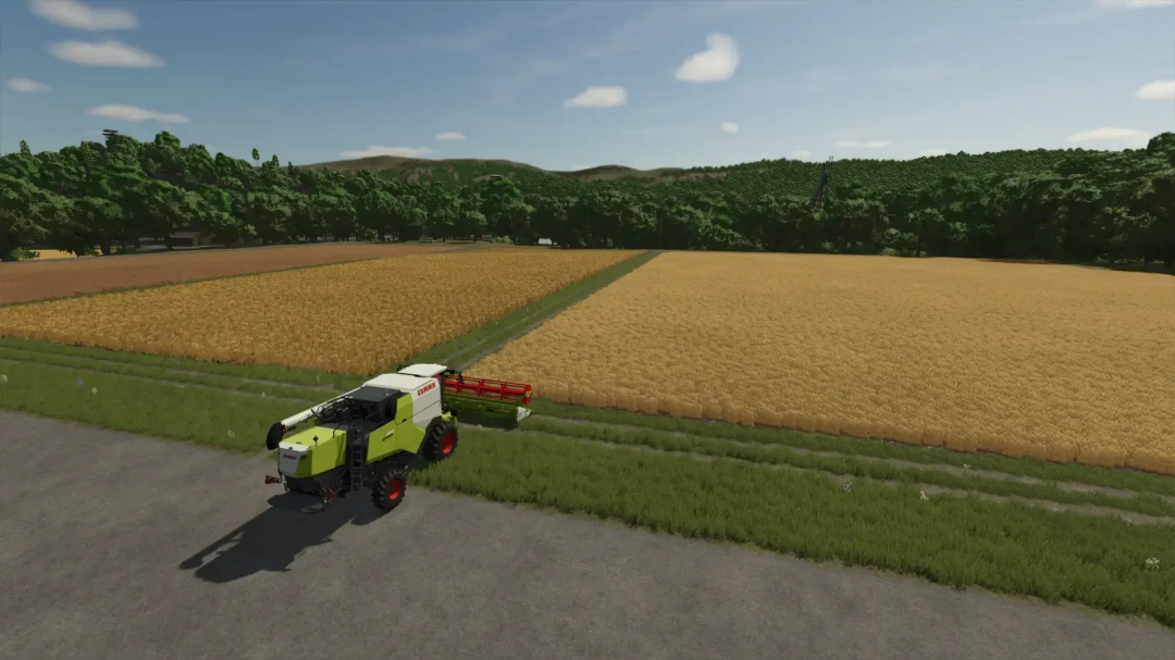 FS25 Volksbend Map v1.0.0.0: Harvester working on a wheat field with lush green hills in the background.