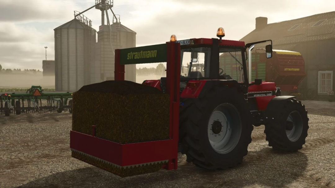 FS25 mod Strautmann Hydrofox v1.0.0.0 attached to a tractor, with silos and buildings in the background.