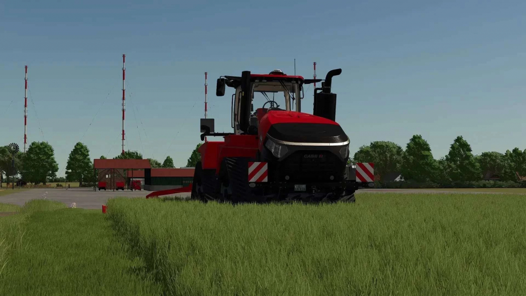 Red tractor in FS25 Papenburg Map 2 4K v2.2.2.0 mod, grass field with farm structures and radio towers in the distance.