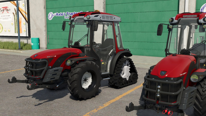 fs25-mods,  Two red Antonio Carraro tractors in Farming Simulator 25 mod pack v1.0.0.0, parked in front of a green building.