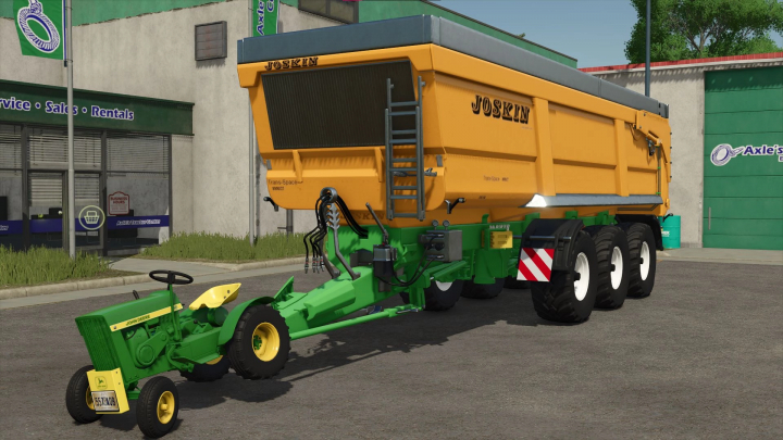 fs25-mods,  Joskin TransSpace 8000 mod in FS25 displayed in front of a store, showcasing its vibrant yellow trailer attached to a green tractor.