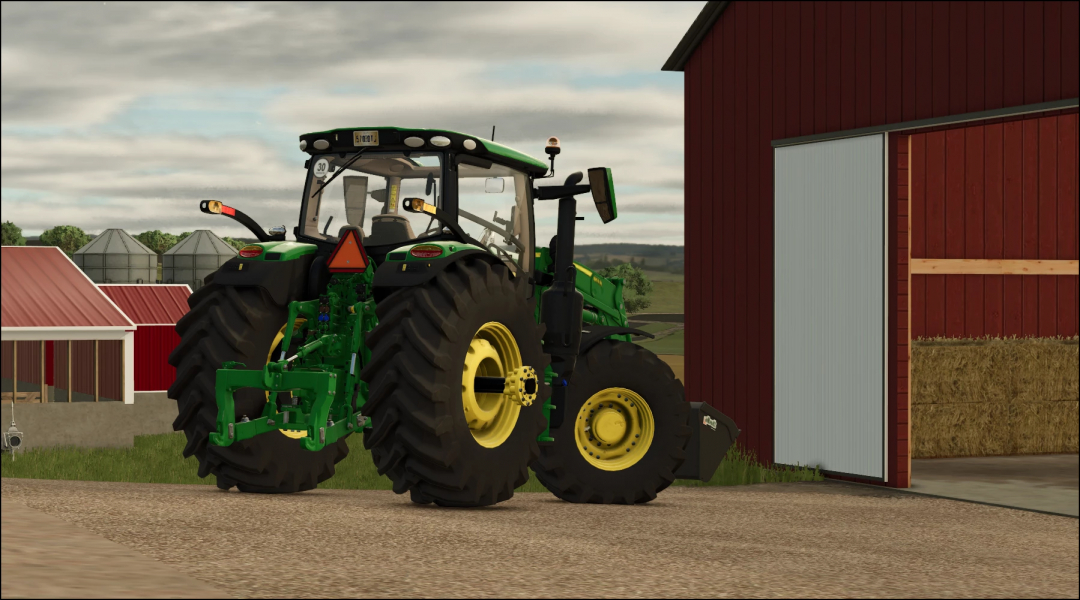 John Deere 6R US tractor mod for FS25 parked near a barn.