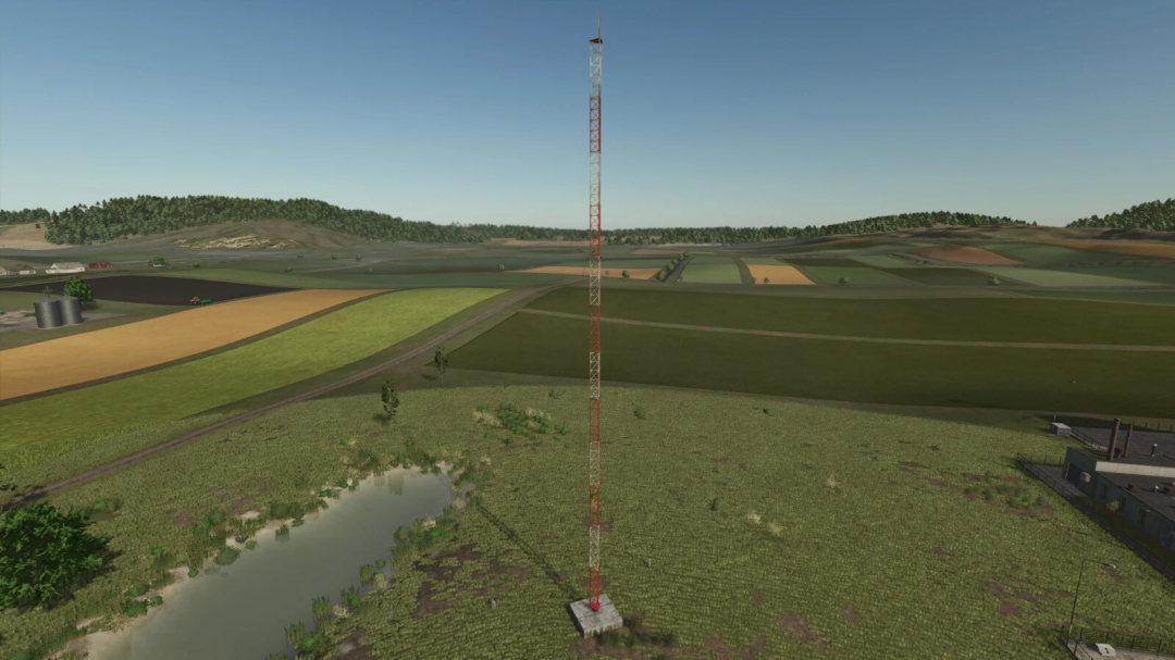 A radio tower mod in Farming Simulator 25 overlooking vast farmland and a pond. FS25 mods enhance the gaming landscape.