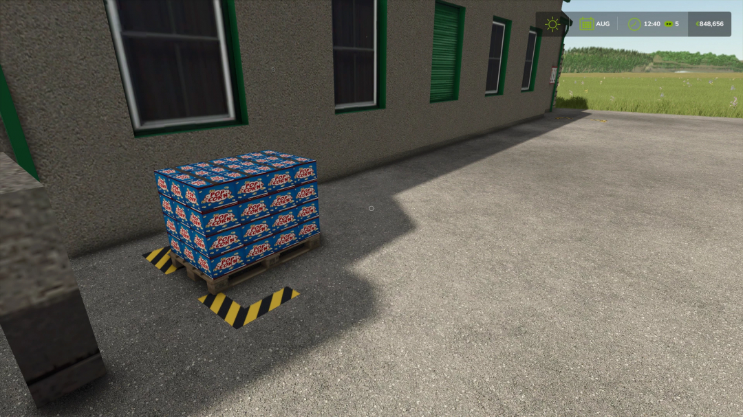 FS25 mod showcasing popcorn production with pallets of popcorn boxes near a building.