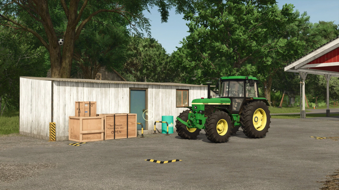 FS25 mod Small Workshop v1.0.0.0 features a rustic shed, crates, and a green tractor in a lush farm setting.