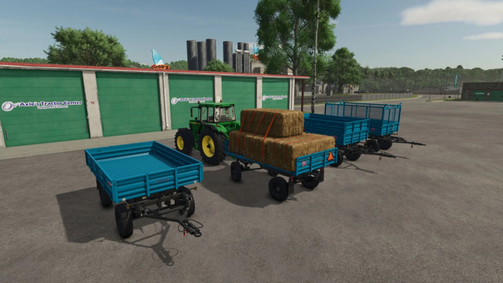 fs25-mods, FS25 mod 2PTS 4.5 v1.0.0.0 showing blue trailers, one loaded with hay bales, next to a green tractor in front of Axle's Tractor Center.