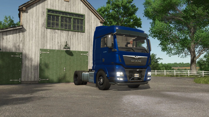 fs25-mods,  FS25 mods: Blue MAN TGX 18500 truck parked in front of a barn in Farming Simulator 25.