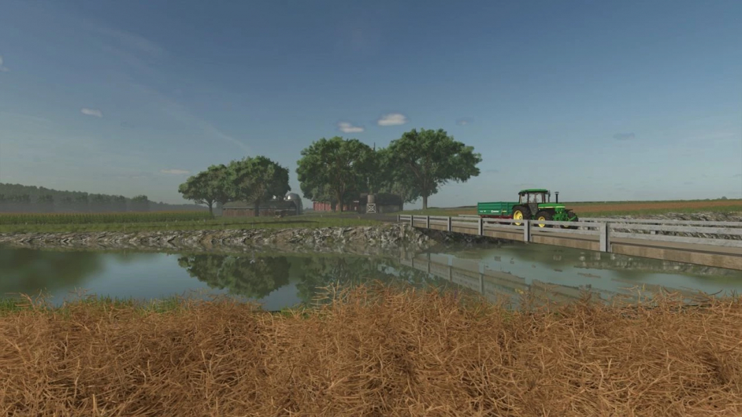 A scenic view of A Long The River Farm mod for FS25 showing a tractor crossing a bridge over a river with trees and farmland in the background.