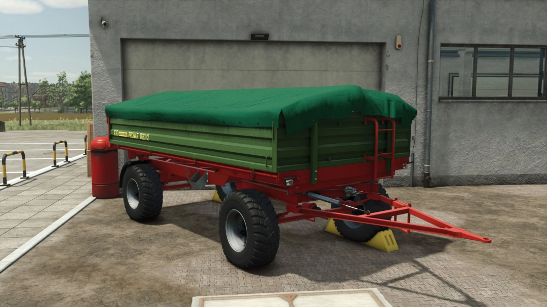 FS25 mod Pronar T653 trailer with green cover, parked outside a building in Farming Simulator 25.