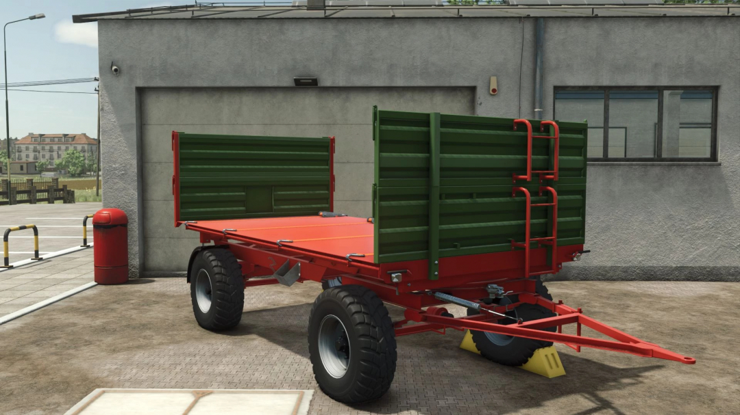 Pronar T653 v1.0.0.0 trailer mod for FS25, featuring a red and green design, parked outside a building.