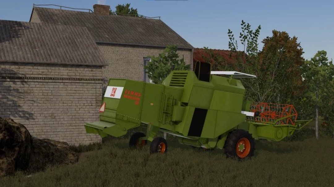 FS22 mod Claas Mercator 50 harvester near a brick house in Farming Simulator 22.