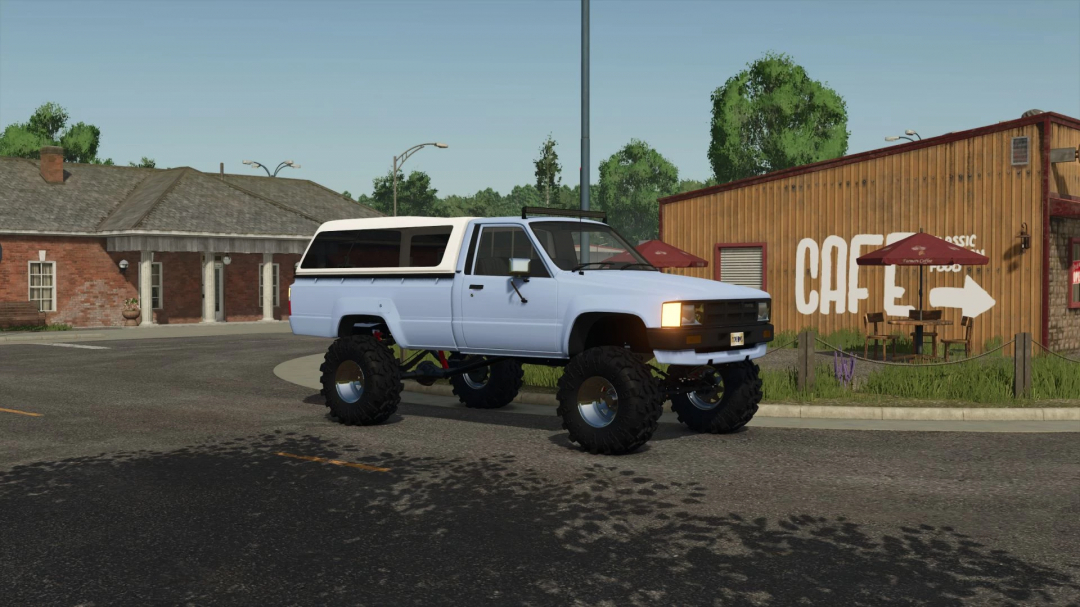 FS25 mod featuring a 1984 Toyota Hilux v1.0.0.0 with off-road modifications, parked near a café.