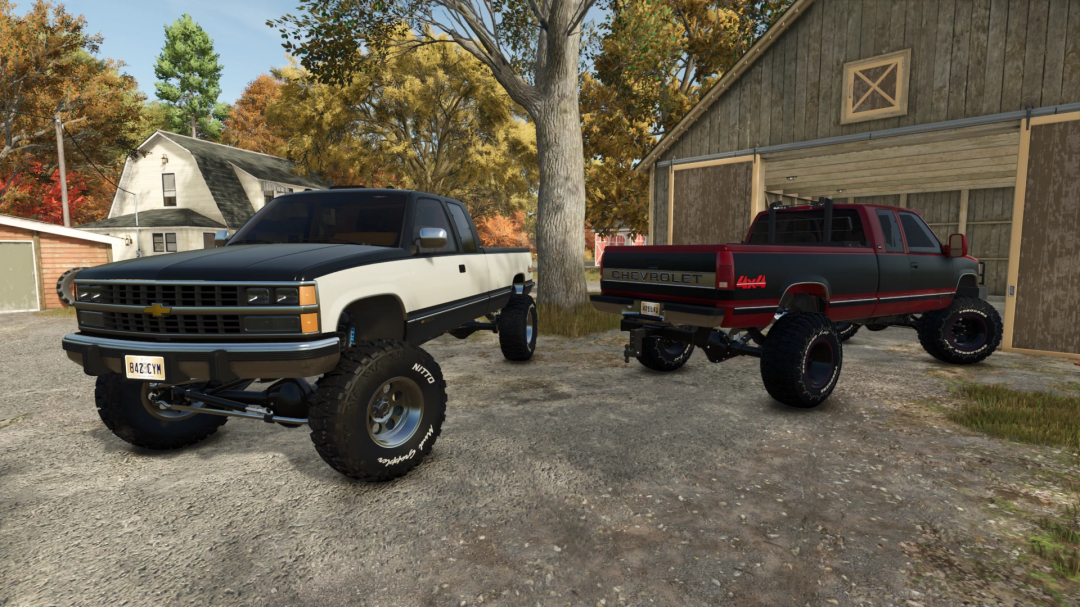 Two modified 1990 Chevy K2500 trucks parked in a farm setting in FS25 mods, showcasing lifted suspensions and custom wheels.