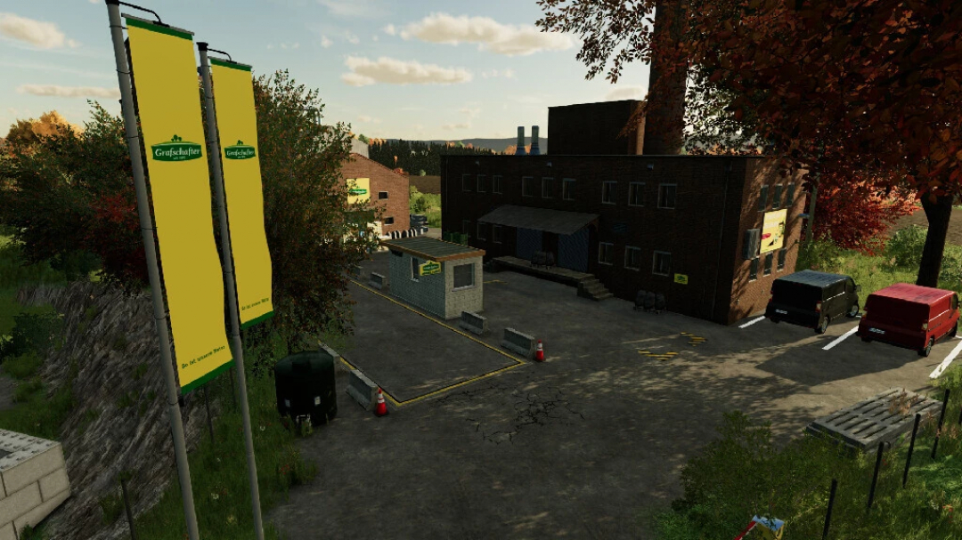 FS22 mod The Eifel TerraLifePlus: industrial building with flags, parked vehicles, and trees in Farming Simulator 22.