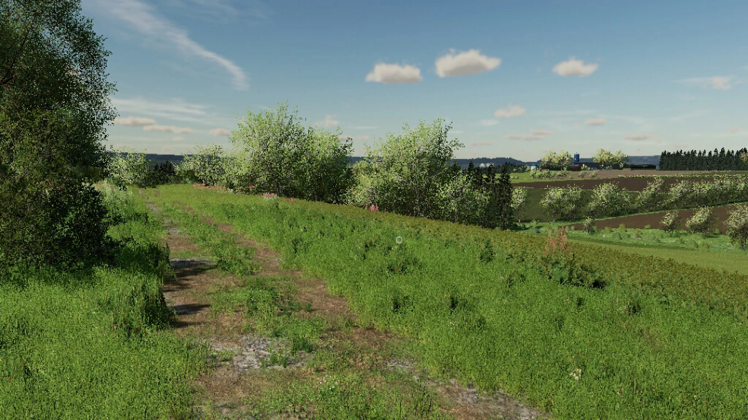 Scenic landscape in FS22 mod Eifel TerraLifePlus v1.2.0.0, showcasing lush fields and trees under a blue sky.