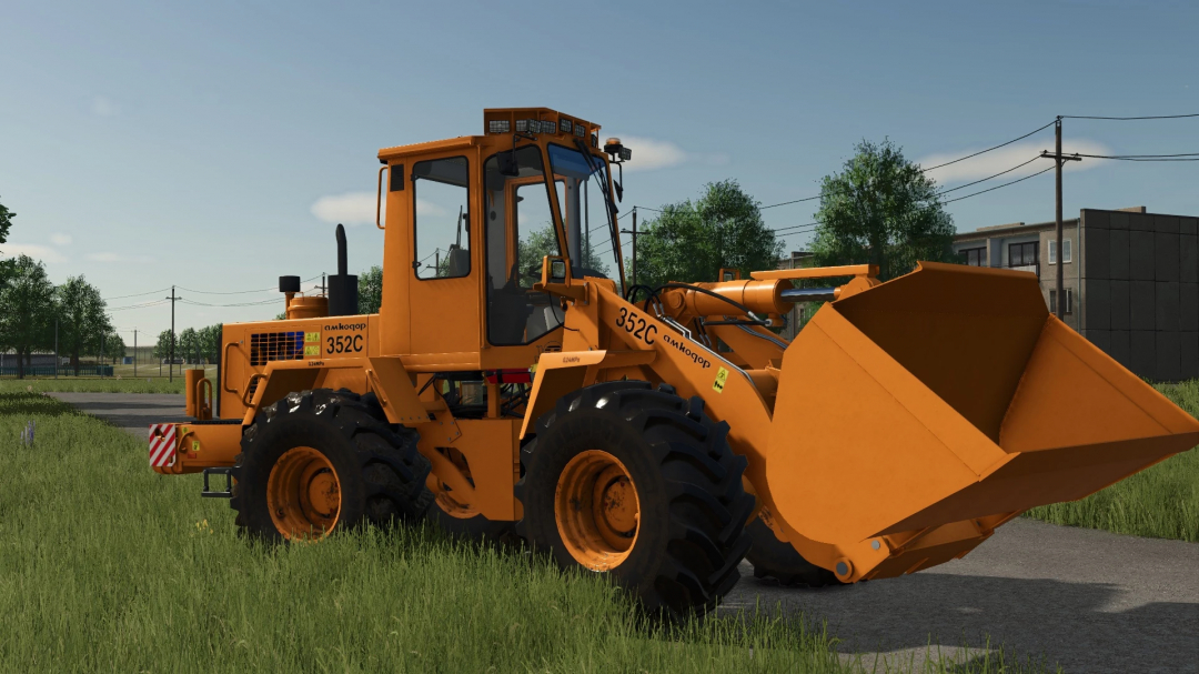 Amkodor-352S loader mod in FS25 game, showcasing a detailed orange construction vehicle on a rural road.