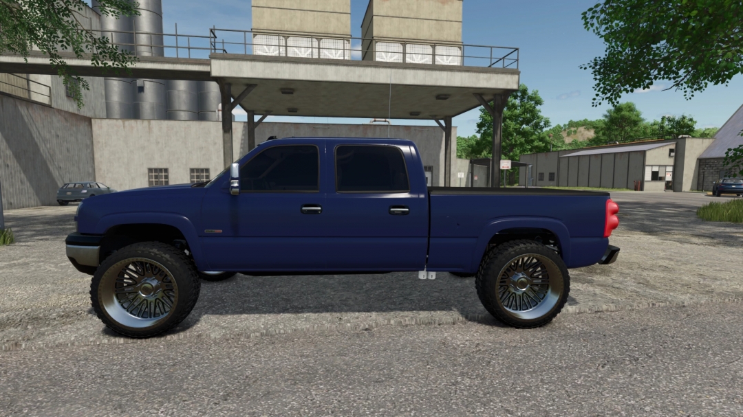 Side view of 2005 Chevy 3500 v4.0.0.0 in FS25 mod, showcasing large tires and blue paint against factory backdrop.