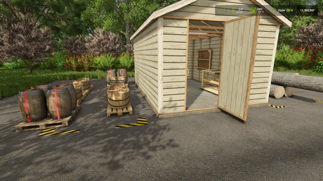 Ultimate Woodshop mod in FS25 with barrels and logs outside a shed.