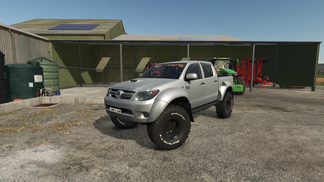 Toyota Hilux AT38 mod parked on a farm in FS25, showcasing large tires and a rugged build.