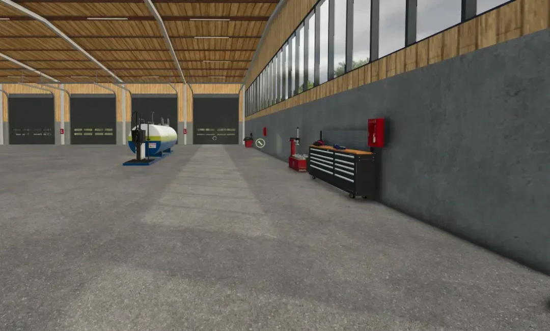 Interior of AustriaModding drive-through hall in FS25 with equipment and storage area.