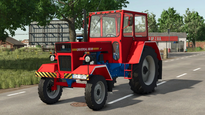 fs25-mods,  FS25 mod U650M v1.0.0.0 showing a red tractor with a cabin, parked on a road with greenery and buildings in the background.