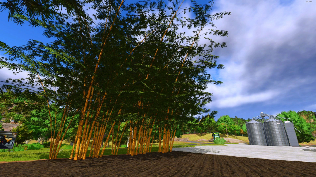 Bamboo grove in FS25 Banbuzal mod with silos in the background under a blue sky.