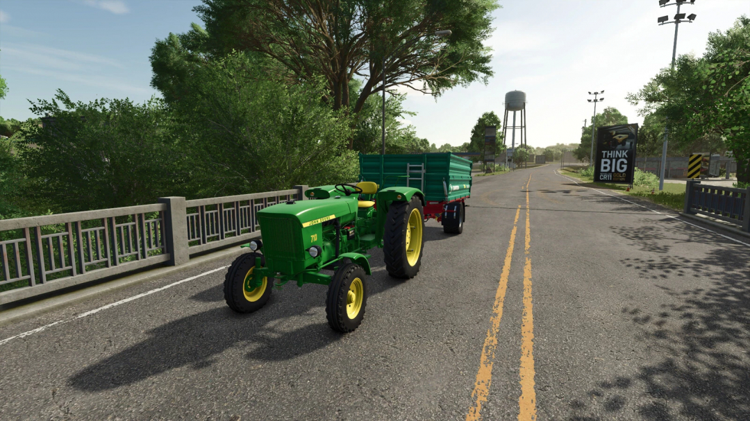 John Deere 710 tractor mod in FS25 with trailer on road, featuring lush green trees and a clear sky.