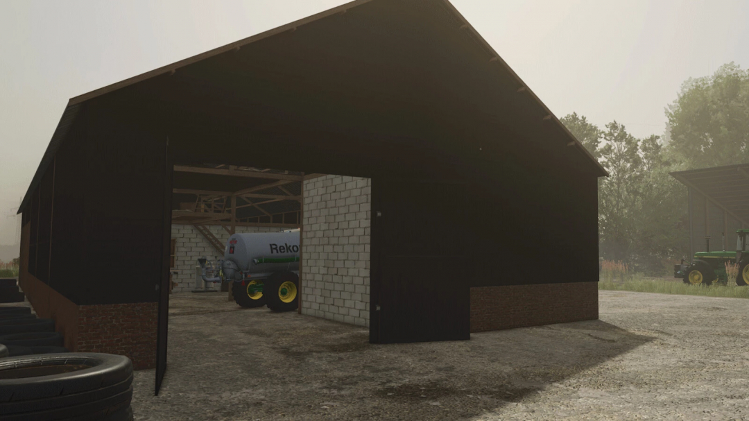 Old German barn mod in FS25 with tractor in the background.