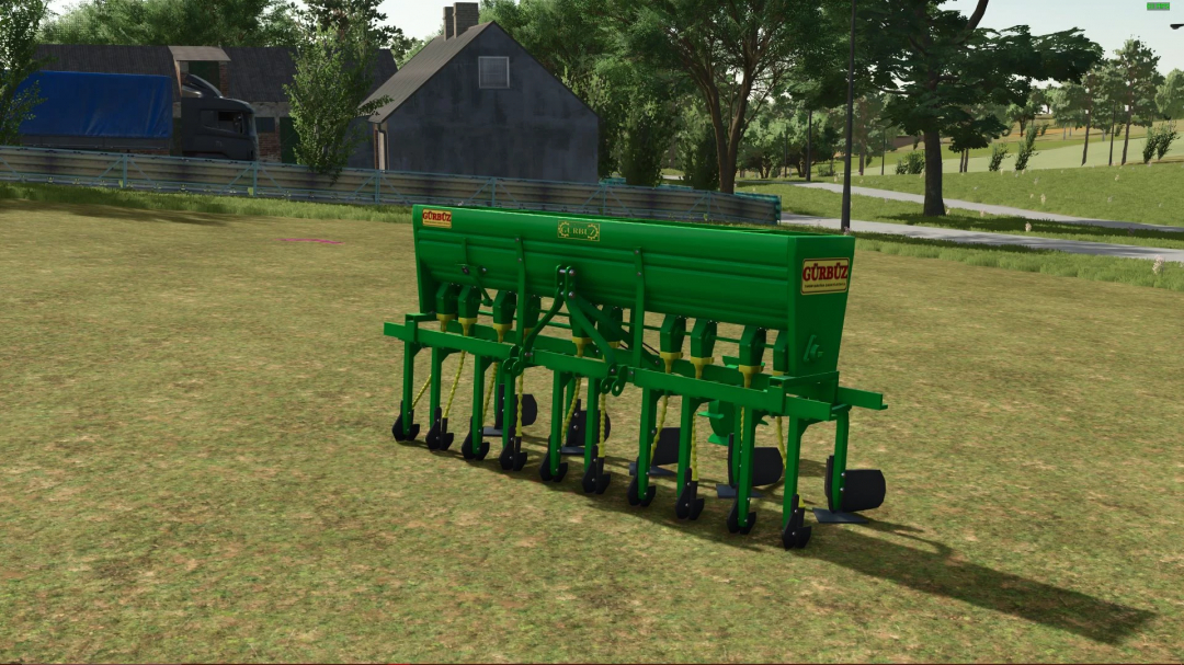 Green Gürbüz Mister v1.0.0.0 mod for FS25 on grass field, background of farm buildings and trees.