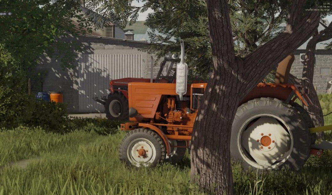 FS22 mods - W?adzio T25 edit v1.0.0.0 tractor next to a tree and shed in Farming Simulator 22.