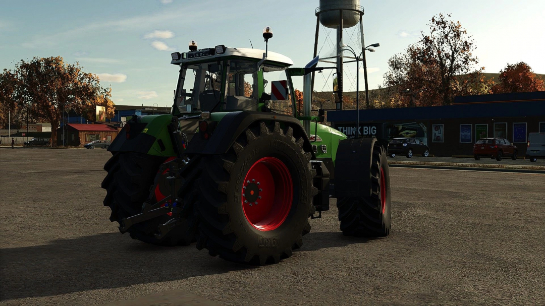 Fendt 900 Gen2 mod for FS25 parked in a lot, surrounded by autumn trees and buildings.