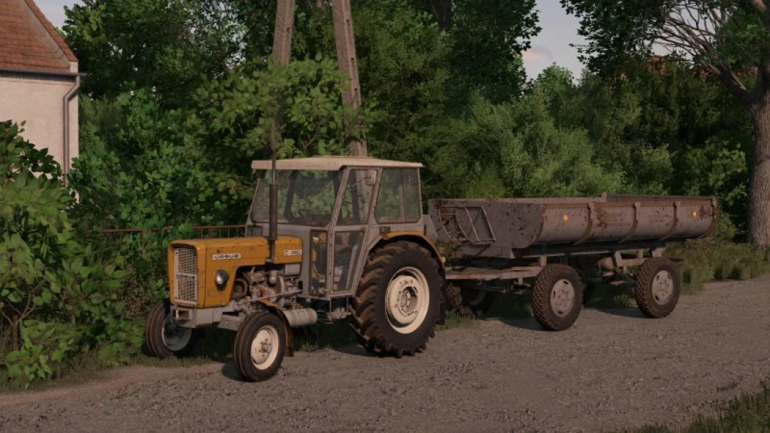 FS25 Ursus c360 3p mod showing a yellow tractor with a trailer on a gravel path, surrounded by trees.