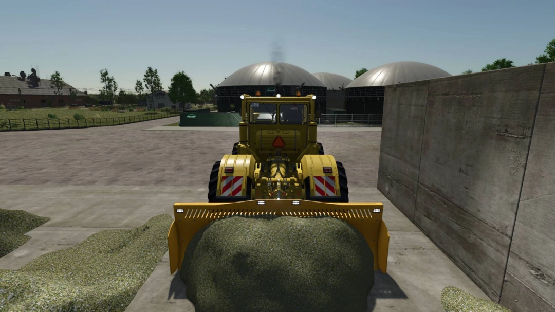 K700 tractor with sliding shield mod in FS25, pushing silage on a farm.